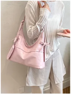 Vista puesta del bolso de hombro en cuero suave rosa con lazos y monedero a juego