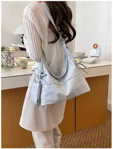 Detalle de un bolso hobo de cuero suave azul claro con nudos y un pequeño monedero