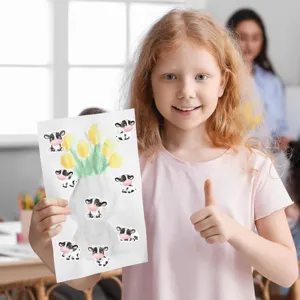A smiling young girl showing a drawing decorated with cute cartoon cow stickers