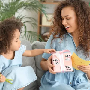 Close-up detail of cute cartoon cow stickers decorating a pink gift box for kids party