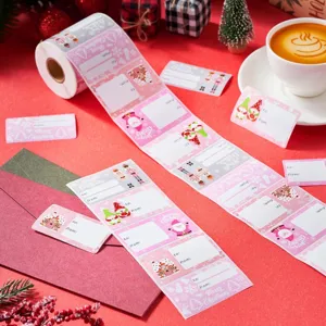 Close-up van roze kerstcadeaustickers met kerstman- en gemberkoekmotieven op een rol.