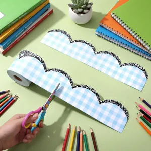Mano cortando una pegatina de borde decorativo a cuadros azul claro para pizarra