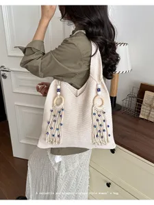 Gestrickte Schultertasche mit Quasten und blauem Auge am Model