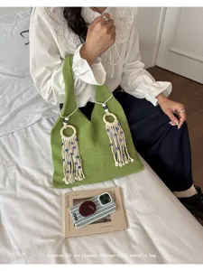 Detailansicht einer grünen handgestrickten Tasche mit eleganten Evil-Eye-Quasten