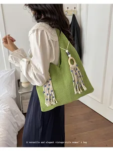 Nahaufnahme einer grünen Strick-Schultertasche mit stilvollen dekorativen Perlenquasten