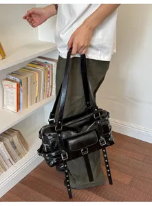 Detail of a large black soft leather tote bag with stylish buckle and eyelet straps.