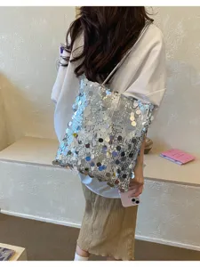 Model carrying a shimmering silver sequined shoulder bag for a trendy summer look.