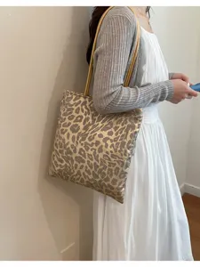 Close-up detail of sequined leopard print tote bag worn over the shoulder by model