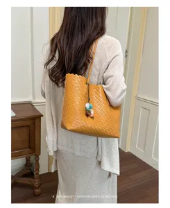 Vista trasera de una mujer con un bolso tote de cuero tejido amarillo mostaza con adornos