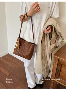 French style woven brown shoulder bag set with beaded charm styled with a trench coat