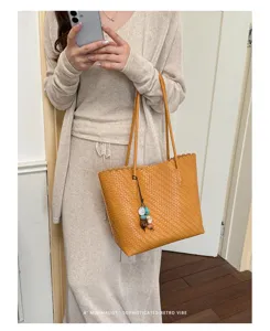Bolso tote tejido naranja minimalista de gran capacidad llevado por una modelo