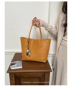 Primer plano de la textura tejida en un bolso tote amarillo de piel suave con dije de piedra