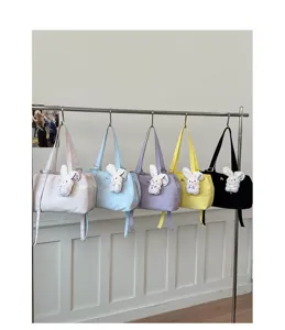 Detailed view of candy-colored nylon tote bags with plush rabbit charms hanging on a rack