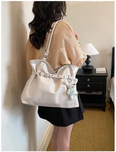 Vue détaillée d'un sac cabas crème brillant avec boucle ceinture et porte-clé ours
