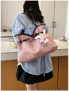 Vue arrière d'un sac cabas rose avec détails de sangles brunes et un charmant lapin en peluche.