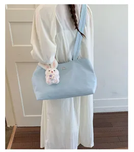 A stylish light blue nylon tote bag with a cute rabbit charm being worn by a model