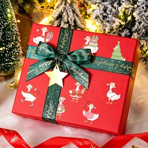 Autocollants mignons de canard blanc de Noël sur une boîte cadeau rouge avec ruban et étoile