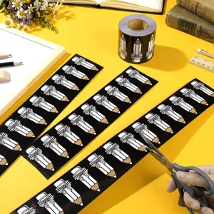 Black pencil bow bulletin board border stickers being cut with scissors for classroom decor