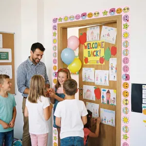 Classroom door frame decorated with pink cartoon smiley face and star border stickers