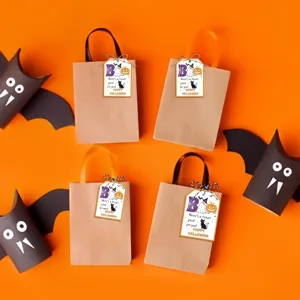 Close-up of cute Halloween ghost and pumpkin tags attached to kraft gift bags for party