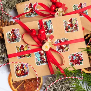 Weihnachtsengel-Aufkleber auf einer Kraft-Geschenkbox mit rotem Band und Zweigen.