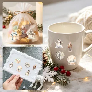 Autocollants de Noël aquarelle sur une tasse blanche, un sac cadeau et une carte de vœux.