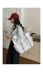 Große weiße Netztasche mit trendigen Buchstabengurten an der Schulter in einem hellen Wohnraum