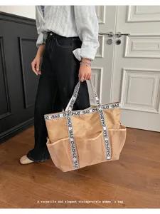 Elegante Frau hält eine große khakifarbene Mesh-Strandtasche mit Logo-Trageriemen