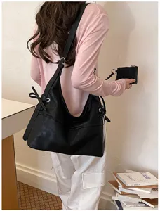 Detailed view of minimalist black soft leather hobo bag featuring a matching small zip pouch