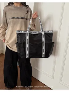 Detailansicht der großen schwarzen Netztasche, die von einem eleganten Model getragen wird.