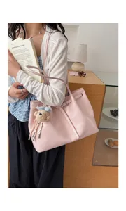Grand sac cabas rose avec détail de ceinture et breloque ours dans un cadre de vie.
