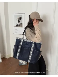 Modell trägt eine große marineblaue Mesh-Strandtasche mit bedruckten Buchstabenträgern