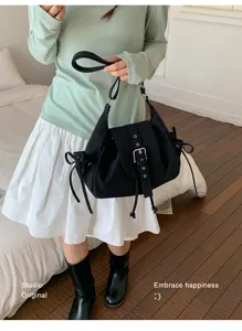 Minimalist black nylon shoulder bag with buckle flap design shown held by a model