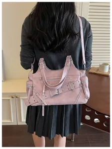 Achteraanzicht van een vrouw met een roze vintage motortas met klinknagels en gespen