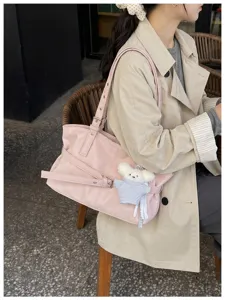 Detailansicht einer rosa Umhängetasche im koreanischen Stil mit Gürtelschnalle und Bärenanhänger
