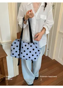 Close-up detail of a light blue canvas tote bag with a stylish large black polka dot print