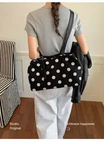 Back view of woman carrying a black canvas tote bag with large white polka dots.