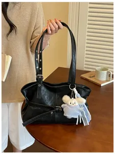Elegante schwarze Schultertasche aus Kunstleder mit Gürtelschnalle und Plüschanhänger