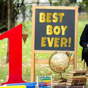 Macro view of "BEST BOY EVER!" golden vinyl letter stickers on a chalkboard.