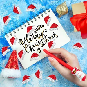 Vista detallada de pegatinas de gorro de Papá Noel con purpurina roja en un cuaderno