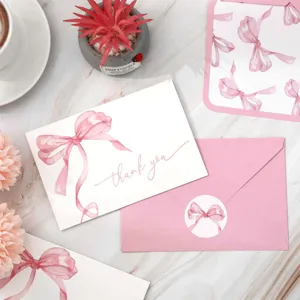 Detalle en primer plano del set de tarjetas de agradecimiento con lazo rosa, sobre y pegatina