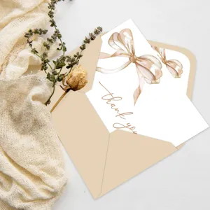 Detalle de la tarjeta de agradecimiento con lazo de acuarela, sobre beige elegante y flores secas