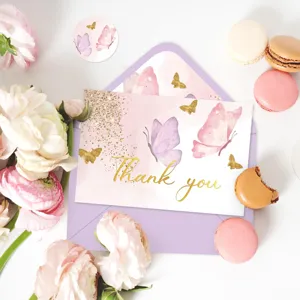 Détail d'une carte de remerciement papillon dorée avec enveloppe lavande et fleurs