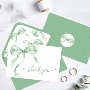 Detalle de tarjeta de agradecimiento en acuarela con lazo verde y sobre color salvia.