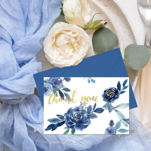 Détail d'une carte de remerciement florale bleue avec texte doré et enveloppe bleue