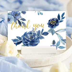 Carte de remerciement florale bleue élégante avec feuille d'or sur un support blanc.