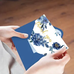 Gros plan d'une carte de remerciement florale bleue avec dorure et enveloppe bleue.