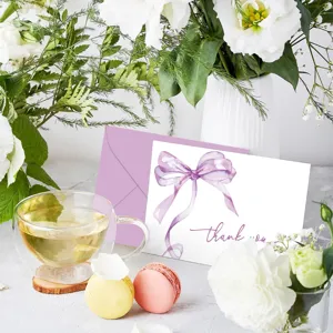 Primer plano detallado de tarjeta de agradecimiento con lazo púrpura y sobre lila