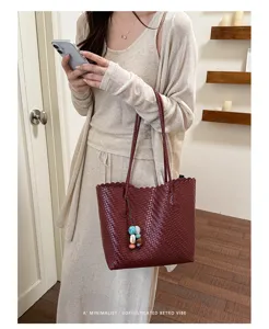 Vista detallada de bolso tote burdeos con textura tejida y colgante minimalista