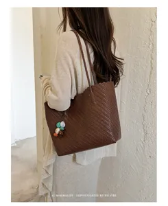 Sofisticado bolso tote de cuero marrón con textura tejida en el hombro de la modelo.